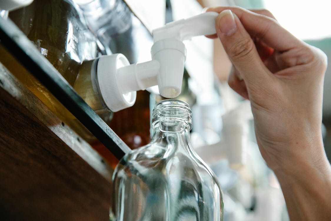 Glasflasche wird an einem Nachfüllhahn befüllt